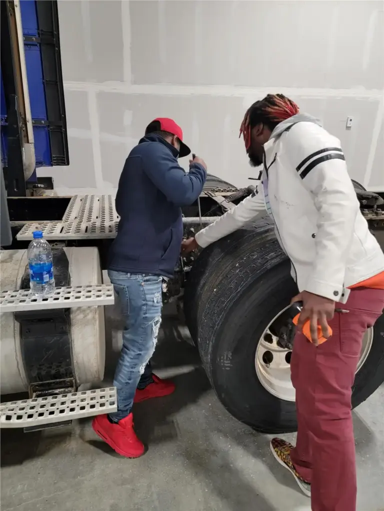 Two men repairing truck tire in a garage