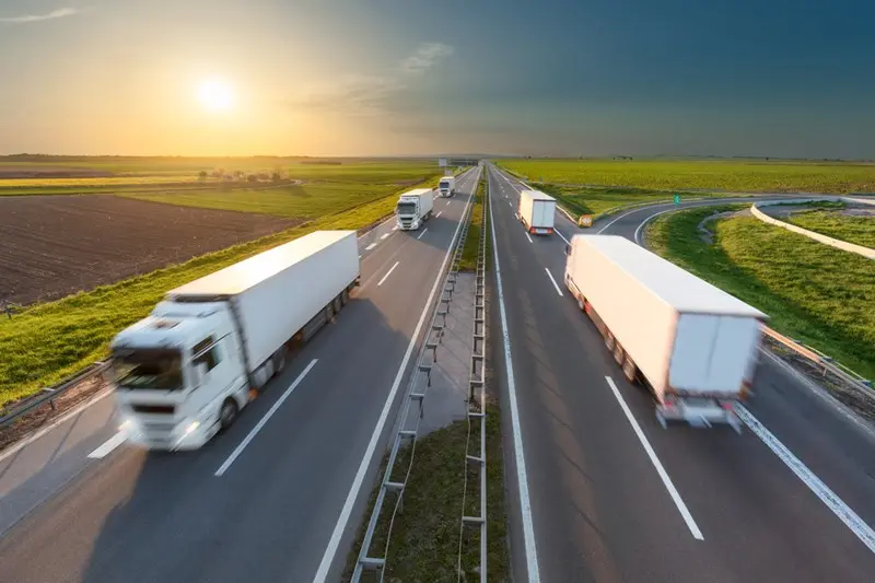 Trucks driving on a highway at sunset