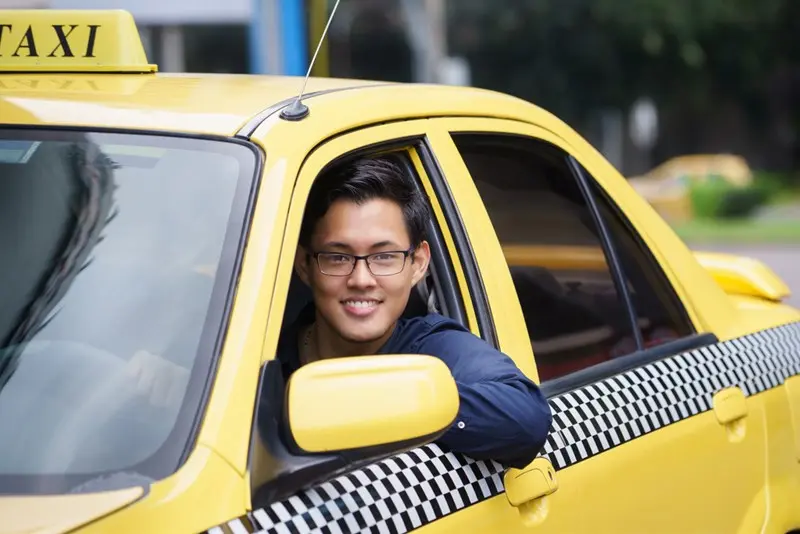 Taxi driver smiling from yellow car window